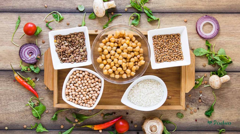 A wooden tray containing a variety of containers containing plant-based protein sources.