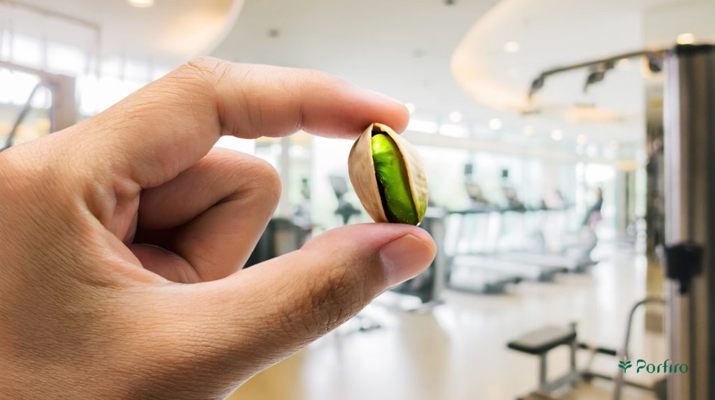 Fingers holding a pistachio in the background of the gym