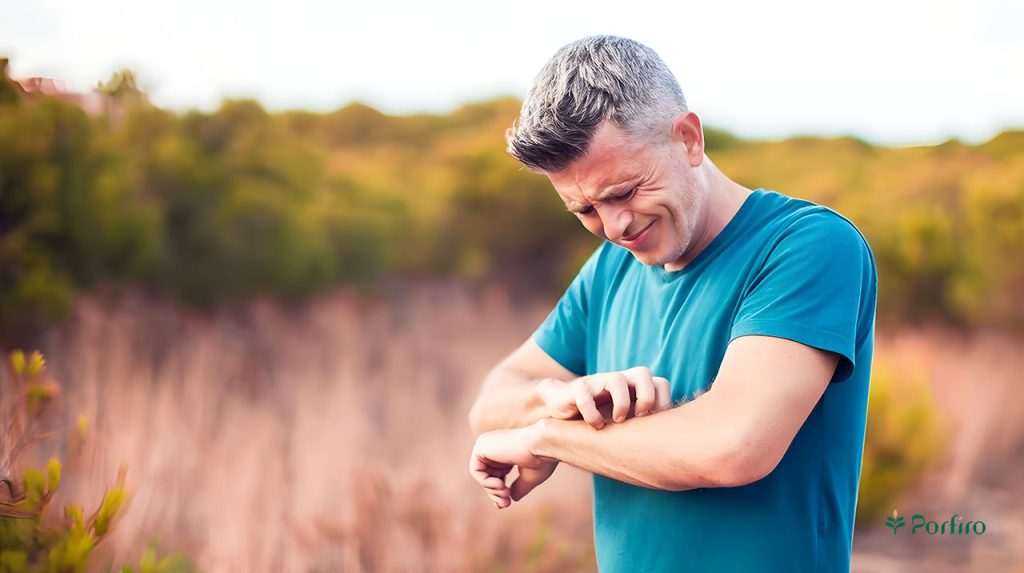 A man stands in a field and scratches his hands due to allergies.