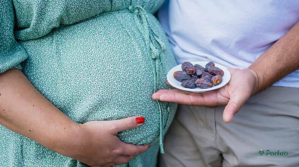 A man holds a container of dates in front of his pregnant wife.