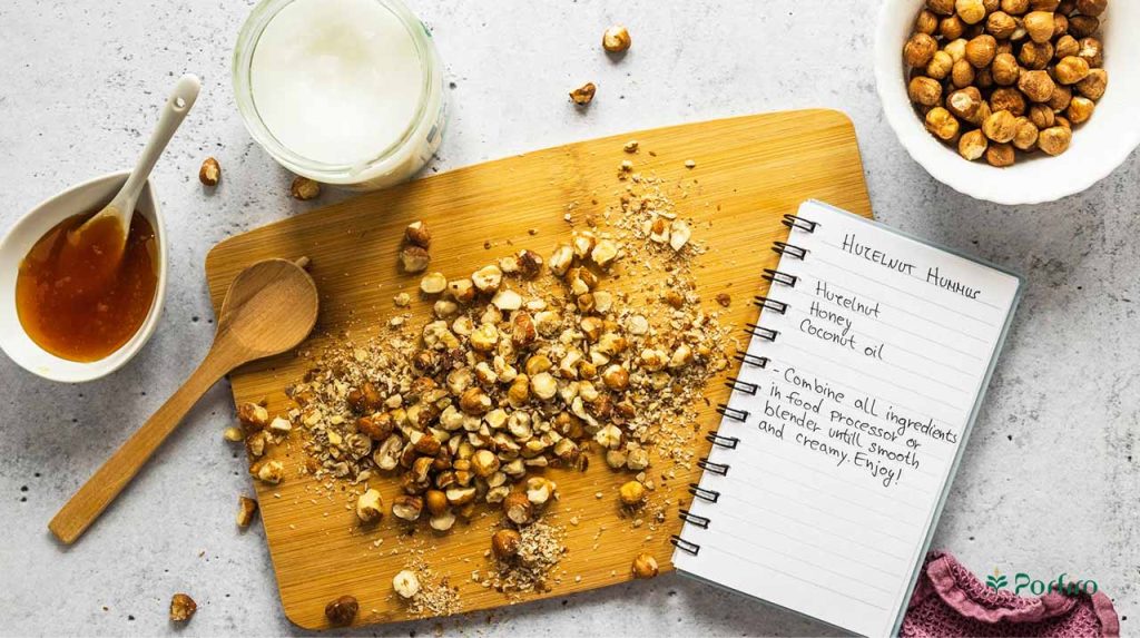 Some chopped hazelnuts on a kitchen board and some in a bowl alongside other ingredients while preparing a snack