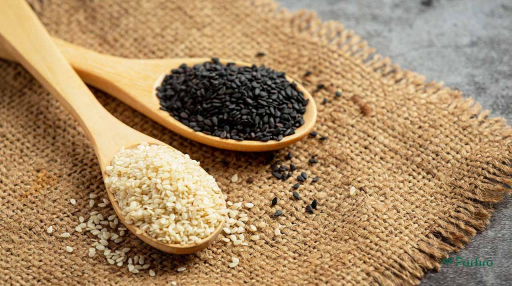Two large wooden spoons filled with black and white sesame seeds, which cause allergies in some people.