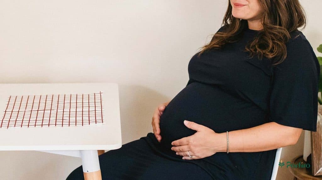 Pregnant woman sitting at her desk with her hands on her stomach