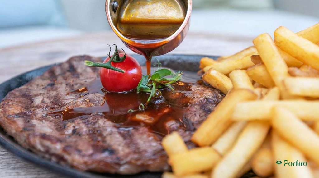 Pouring sauce on steak with french fries