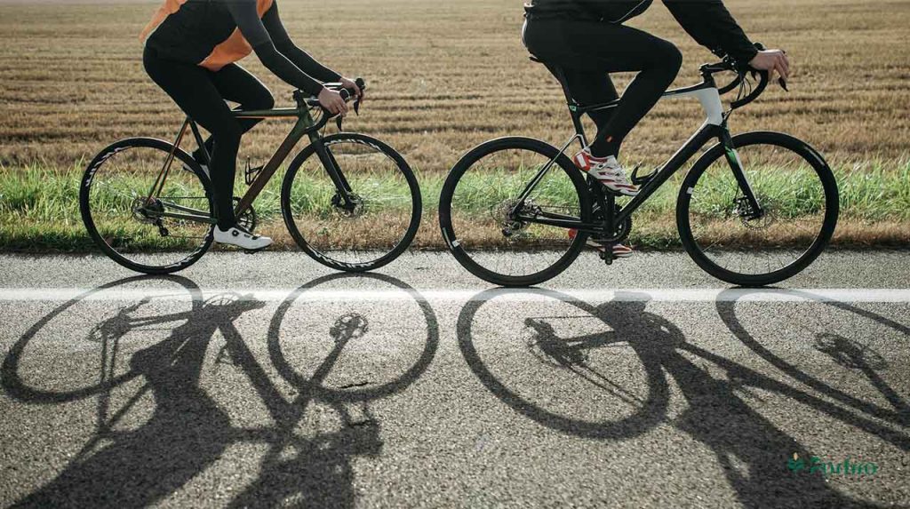 Two people are riding bicycles, following each other