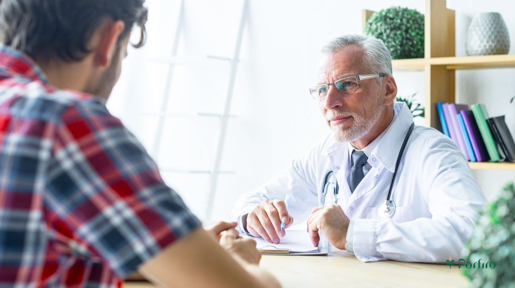 The man is sitting facing the doctor and talking to him.