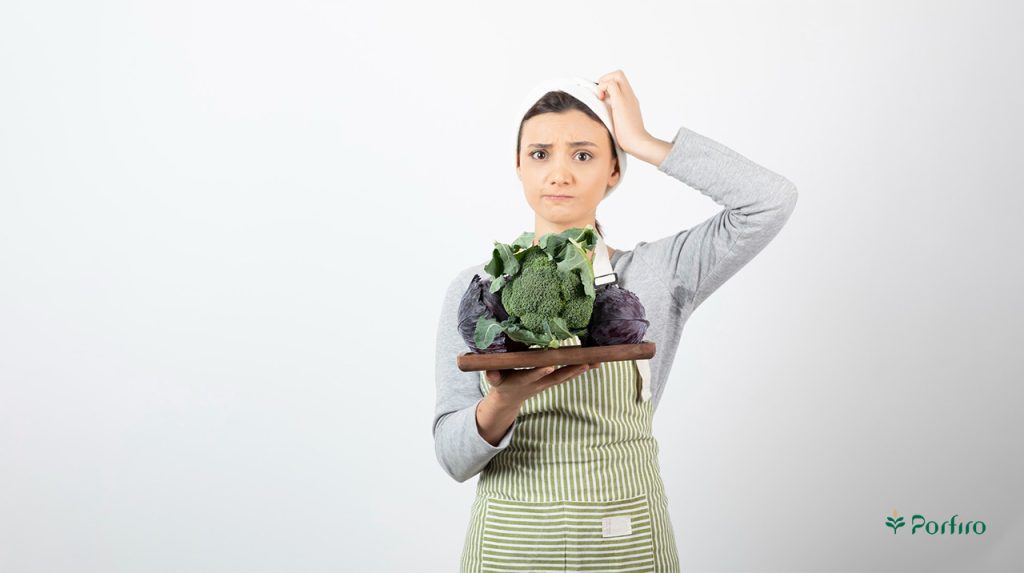 خانمی یک سینی پر از مواد غذایی در دست دارد و برای خوردن آن شک دارد