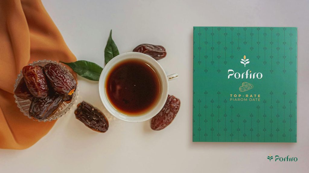 A pack of Piarom Porfiro dates next to a cup of tea and date seeds