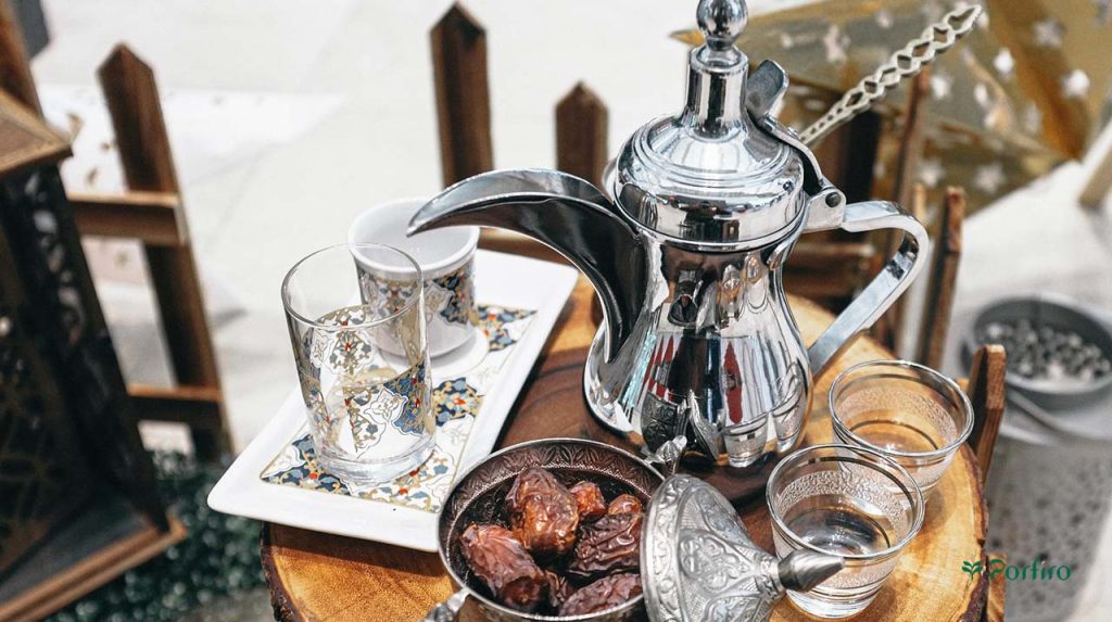 یک قوری و چند فنجان قهوه عربی در کنار یک ظرف خرما