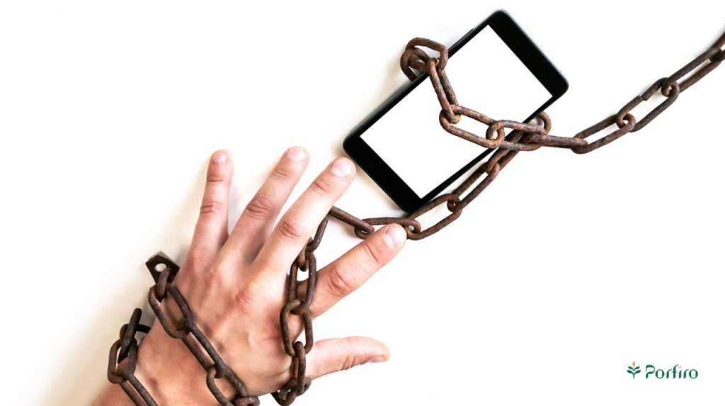 A person's hand locked to their phone with a large iron chain to illustrate why social media is so addictive.