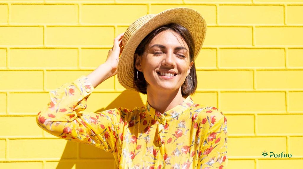 A woman wearing a straw hat stands facing the sunlight and enjoys it.
