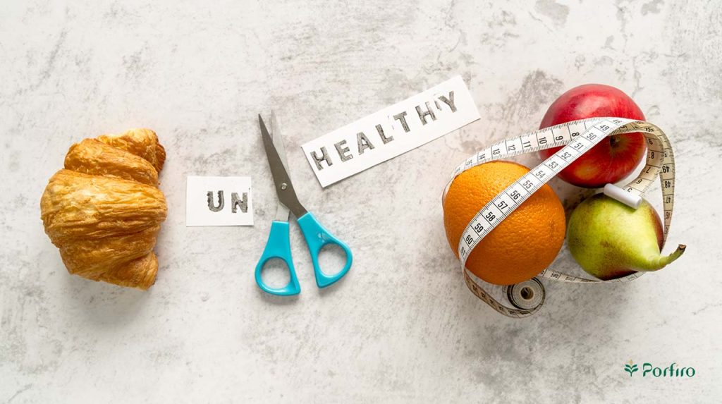 Healthy and unhealthy food on both sides where the word unhealthy has been cut on paper with a pair of scissors and turned into two sides, un and healthy.