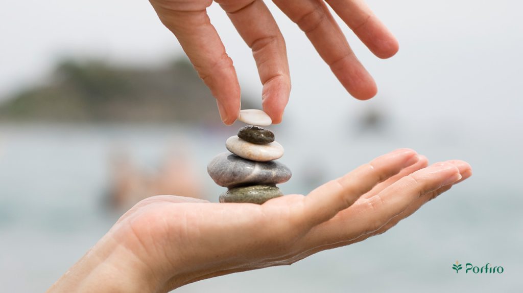 A person tries to arrange small pieces of rock on her hand into a column.