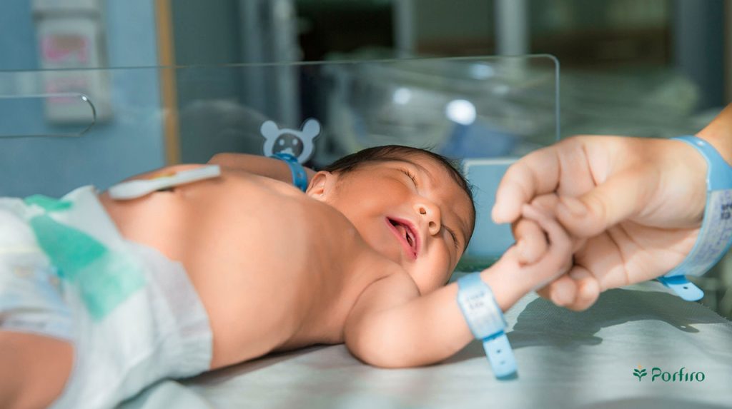 A newborn baby in a hospital setting receiving care to prevent phenylketonuria.