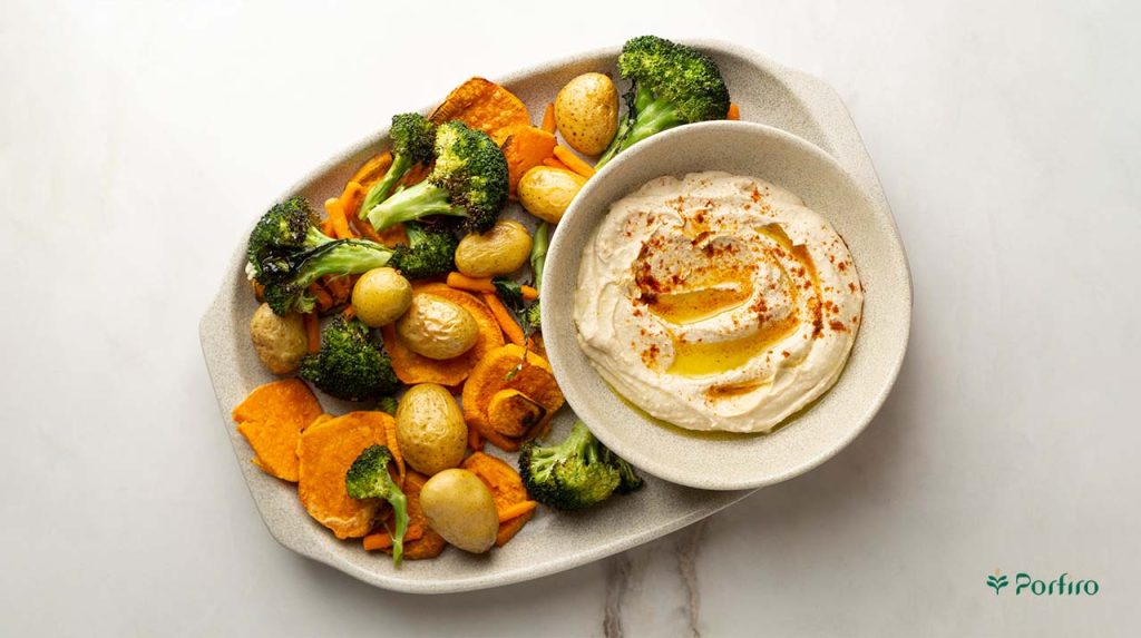 A plate full of French fries and steamed broccoli next to a bowl of hummus garnished with olive oil for the article Vegetarian Diet: A Beginner’s Guide and Meal Plan on Porfiro’s blog